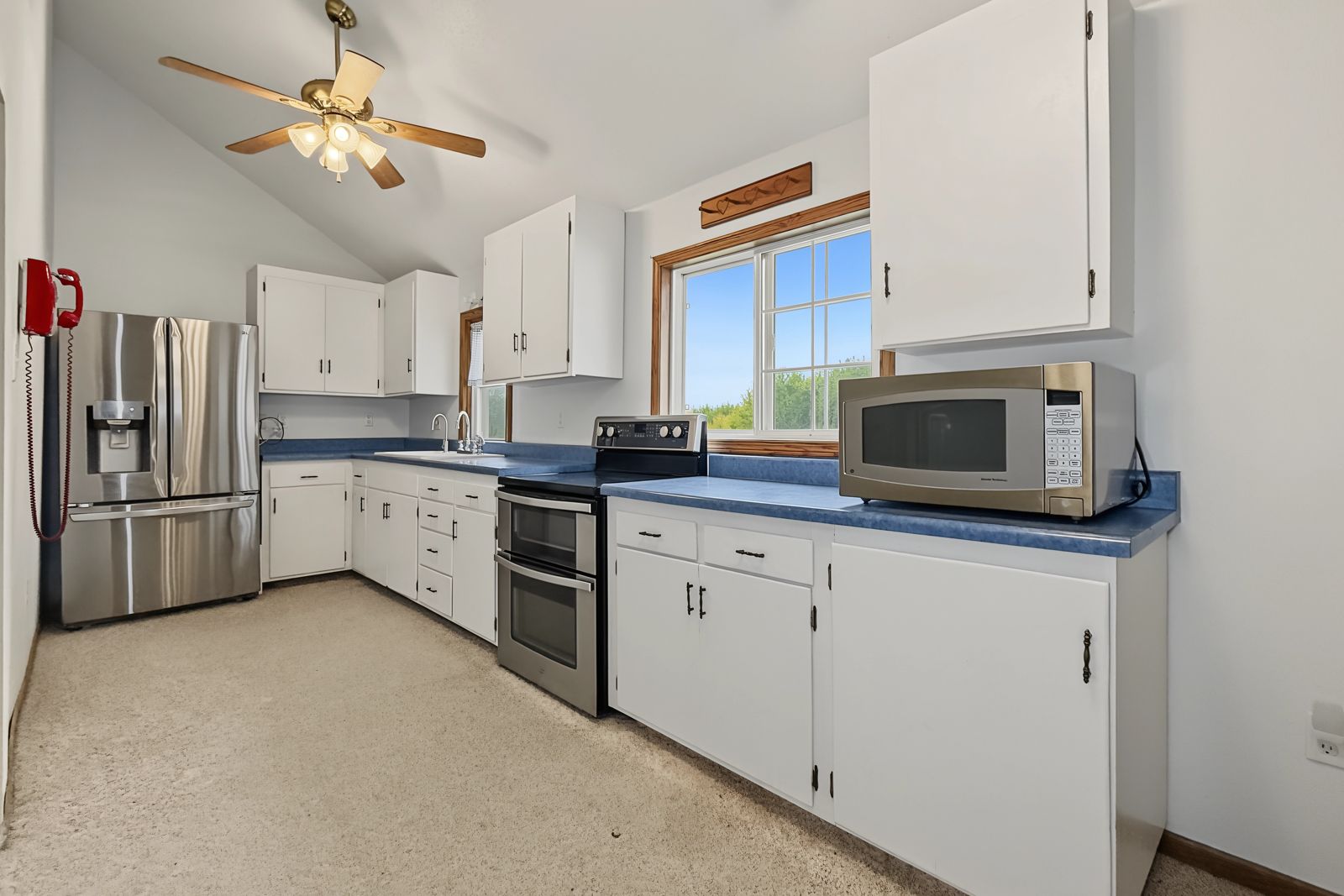 260 County Line Rd, Runnells — Vaulted kitchen with white cabinets and stainless appliances
