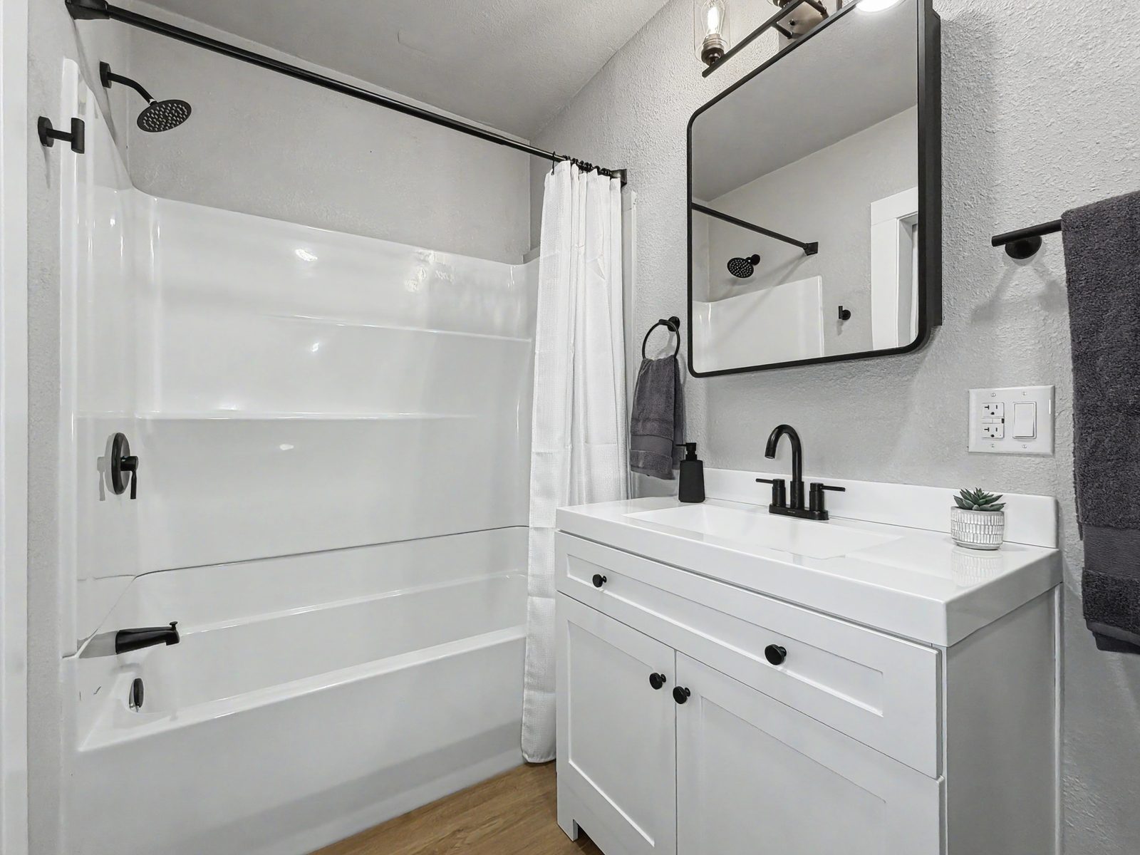 Renovated bathroom with new vanity, tub surround, and black hardware at 3436 Scott Ave Des Moines Iowa 50317