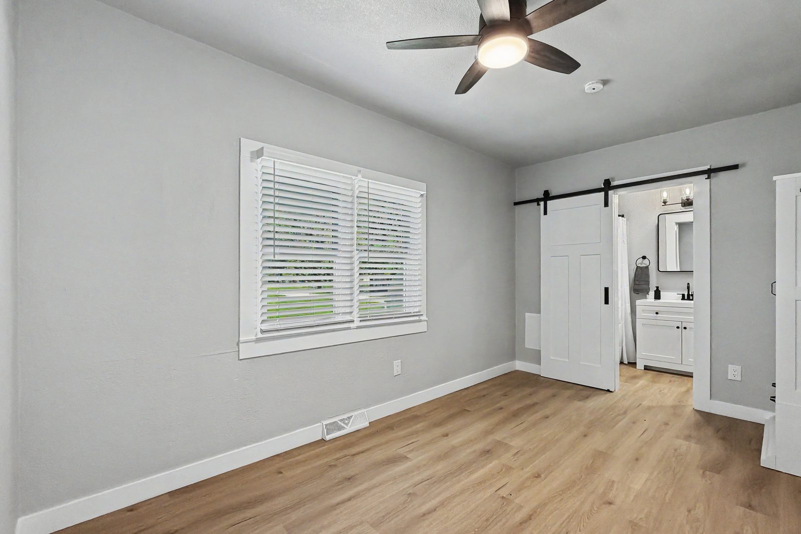 Bedroom with barn door and LVP flooring in renovated ranch home Des Moines Iowa