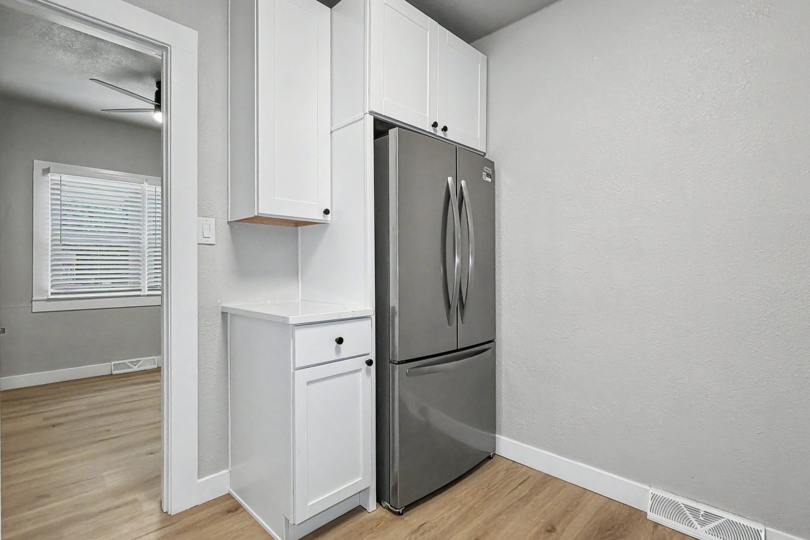 Updated kitchen with stainless refrigerator and white cabinetry in renovated Des Moines ranch home