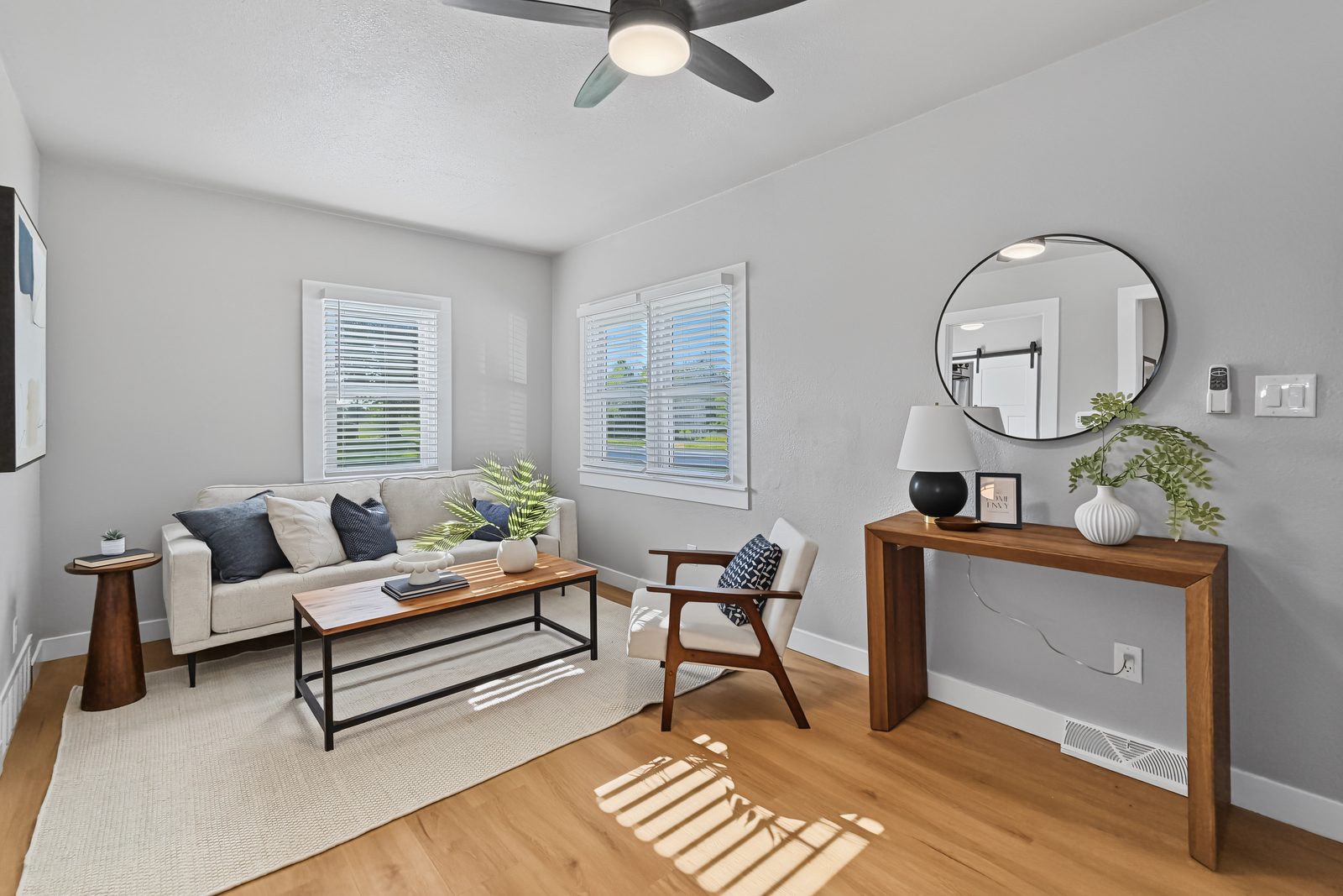 Staged living room with sofa, walnut console, and two front windows at 3436 Scott Ave Des Moines Iowa 50317