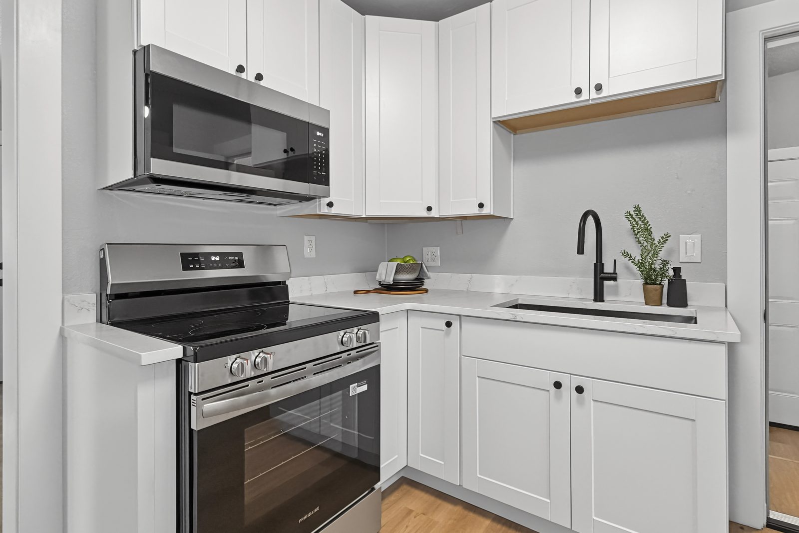 Renovated kitchen with white shaker cabinets, quartz counters, and stainless range at 3436 Scott Ave Des Moines