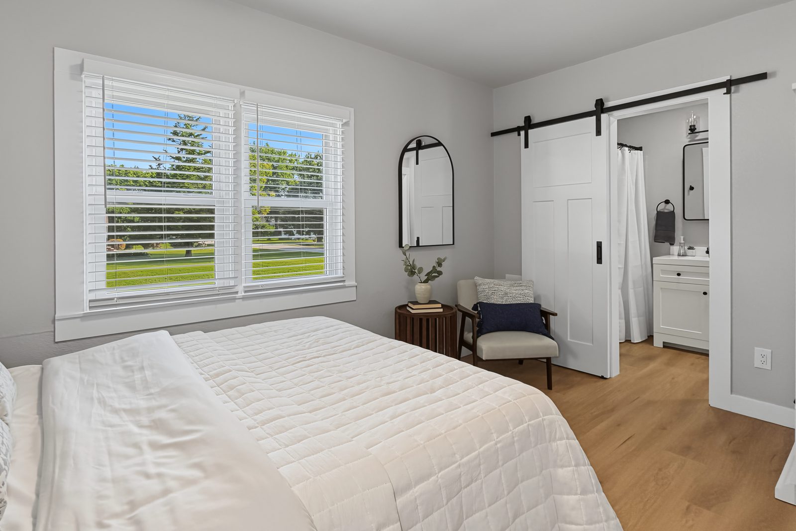 Primary bedroom with sliding barn door to the bathroom and two windows at 3436 Scott Ave Des Moines