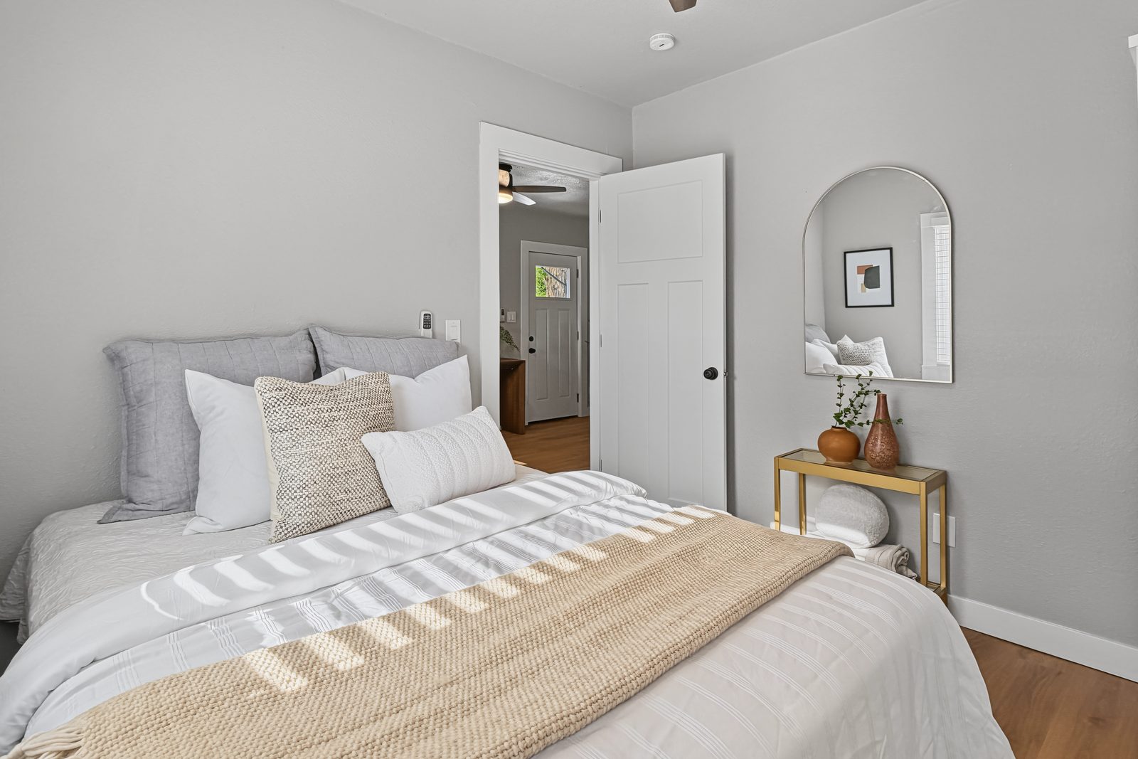 Third bedroom staged with neutral bedding and arched mirror at 3436 Scott Ave Des Moines Iowa 50317