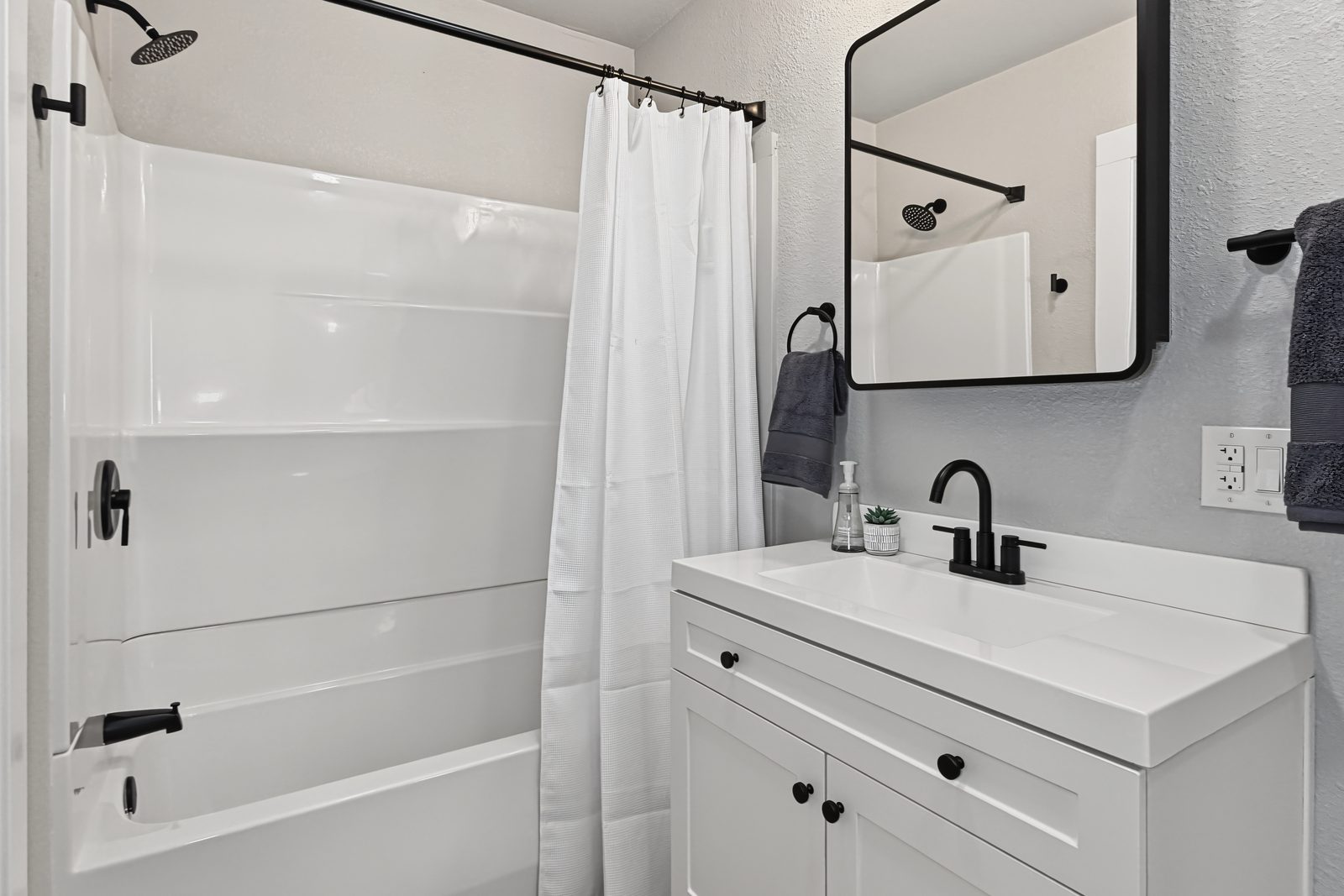 Renovated bathroom with tub surround, new vanity, and matte black fixtures at 3436 Scott Ave Des Moines